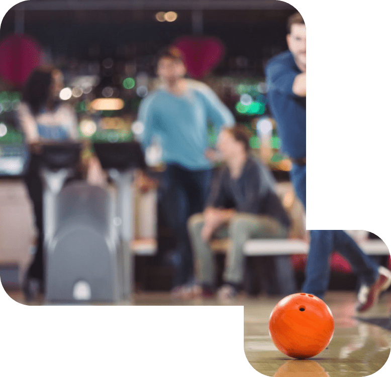 Orange bowlingkugle kastes af mand på bowlingbane